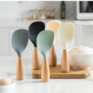 Cucharas para arroz con mango de madera en varios colores, diseño vertical antiadherente, utensilios de cocina organizados sobre tabla de madera.