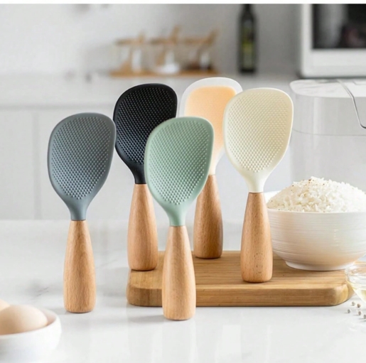 Cucharas para arroz con mango de madera en varios colores, diseño vertical antiadherente, utensilios de cocina organizados sobre tabla de madera.