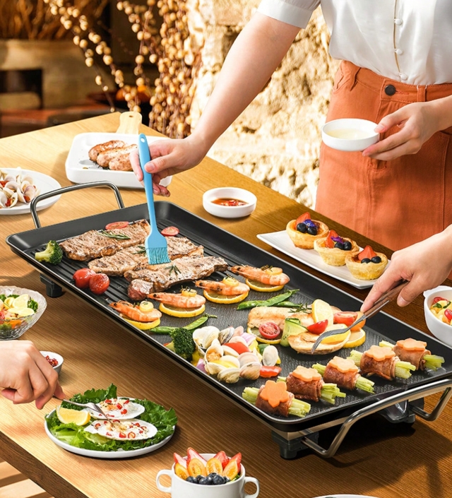 Bandeja eléctrica Aoran 1 con alimentos variados, cocinando en dos zonas sobre superficie antiadherente, ideal para compartir en familia