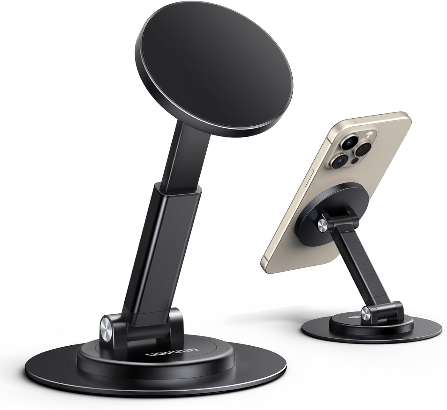 Two black UGREEN magnetic phone stands with circular bases and adjustable arms, each featuring a round magnetic pad for holding smartphones. One stand is empty, while the other supports a gold iPhone with triple cameras, demonstrating the MagSafe attachment and flexible viewing angles.