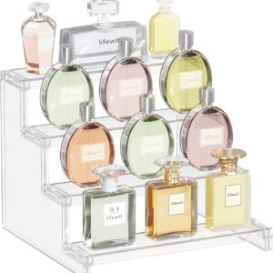Clear acrylic three‑tier perfume organizer displaying assorted Lifewit perfume bottles in pink, green, yellow, amber, and clear tones. Each bottle neatly arranged on stepped shelves, showcasing an elegant and organized vanity display.