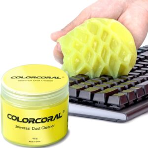 Hand pressing yellow ColorCoral cleaning gel into a computer keyboard to remove dust and debris, with a labeled container of ColorCoral Universal Dust Cleaner (160 g) beside it.