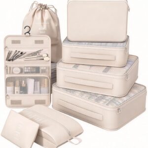 A coordinated set of eight cream‑colored travel packing cubes and organizers displayed neatly on a white background. The collection includes four rectangular zippered cubes with mesh tops, a drawstring laundry bag, a hanging toiletry organizer with compartments holding brushes and bottles, a flat pouch, and a pillow‑shaped zip bag. Each piece features minimalist text such as “WISH U HAVE” and “WISH U HAVE A COLORFUL LIFE ANYWHERE YOU GO,” highlighting its stylish, modern design for organized travel.