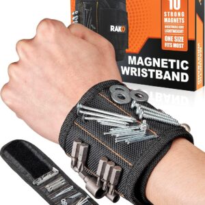 A black RAK magnetic wristband with orange stitching worn on a wrist, holding various metal tools including screws, nails, washers, and drill bits. The wristband’s durable fabric and embedded magnets are clearly visible. Behind it, the orange and black product box displays text highlighting “10 strong magnets,” “breathable and lightweight,” and “one size fits most.” A flat view of the wristband shows how small metal parts can be organized for easy access during work.