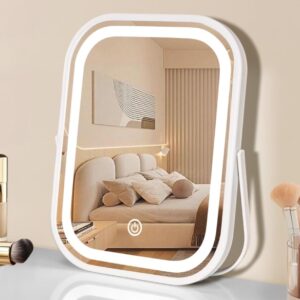 Espejo de maquillaje LED rectangular sobre una mesa, con botón táctil y luz suave, reflejando un dormitorio acogedor; rodeado de brochas y maquillaje.