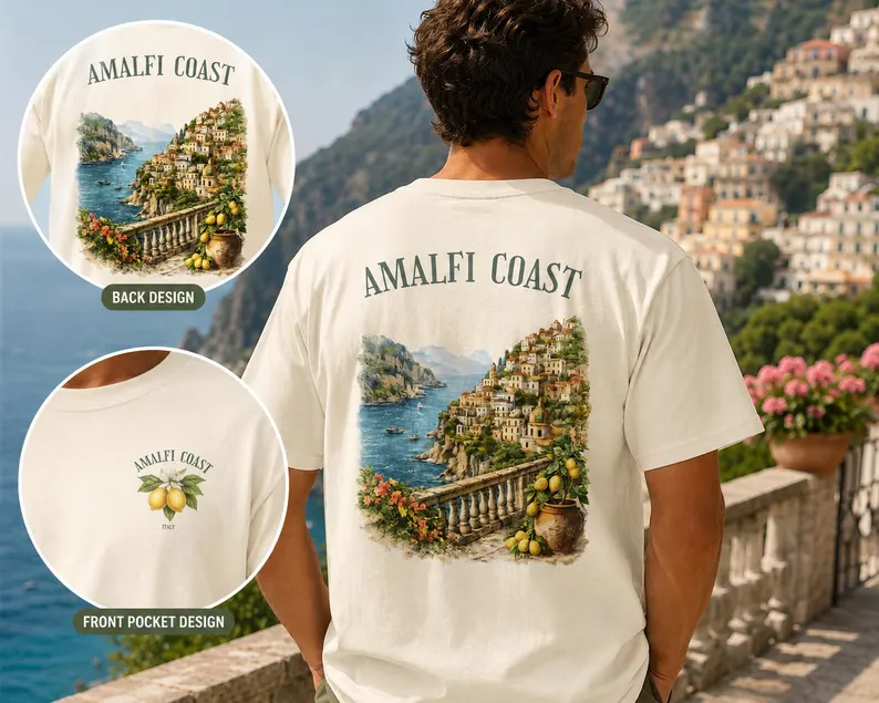 A cream amalfi coast shirt featuring a detailed illustration of Italy’s coastal cliffs and sea view on the back, with a lemon design and “Amalfi Coast” text on the front pocket, styled outdoors in a Mediterranean setting.